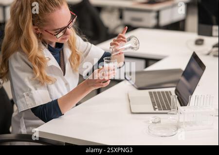Caucasian woman in a medical gown doing laboratory experiments.  Stock Photo