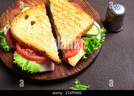 Club sandwich cut in half close up. Ham and cheddar cheese sandwich with vegetables and lettuce for healthy lunch. Stock Photo