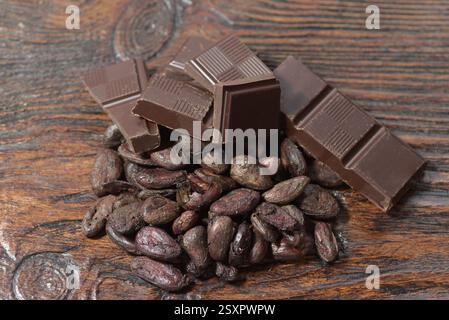 Broken dark chocolate and cocoa beans on the table Stock Photo