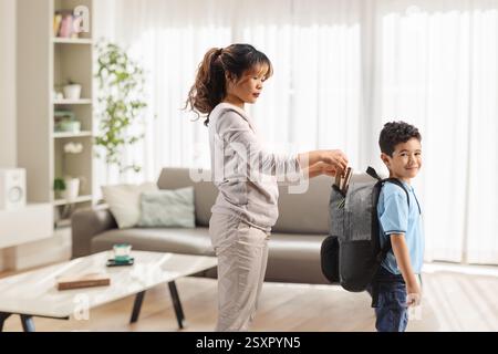 Mother packing a boys school backpack at home Stock Photo