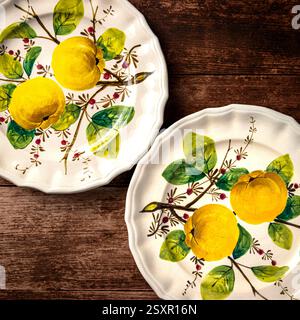 Two antique plates with a yellow fruit design on them. The plates are placed on a wooden surface. The plates have a bright and moody appearance Stock Photo