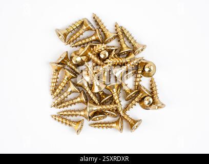 A pile of gold colored screws lies on a white surface ready for various projects Stock Photo