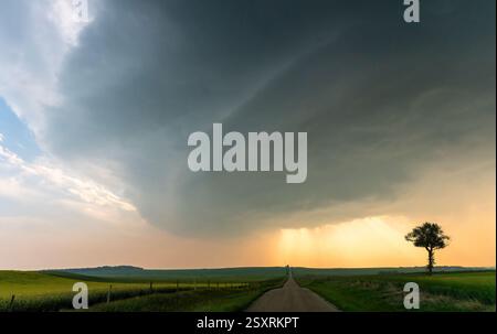 Dramatic supercell thunderstorm forming over a country road at sunset Stock Photo
