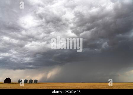 Dark storm clouds gathering over a farm in the prairie Stock Photo