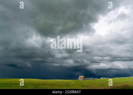 Ominous supercell storm clouds gathering over a lonely abandoned barn in the vast great plains Stock Photo