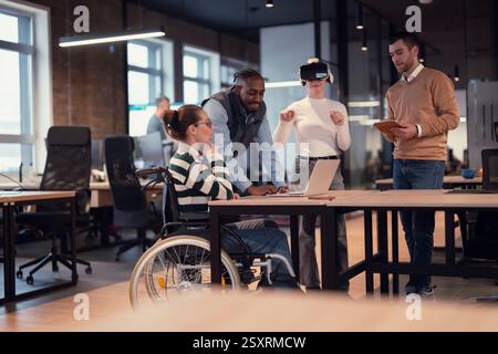 Disabled businesswoman in a wheelchair working in modern coworking office. Team around is using virtual reality goggles, collaborating with the latest Stock Photo
