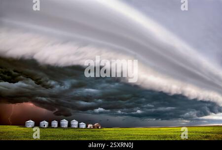 Dramatic supercell thunderstorm shelf cloud forming over a farm with lightning strike Stock Photo