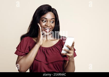 Emotional black woman using nice mobile app on smartphone Stock Photo