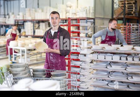 Enthusiastic ceramicist demonstrating handcrafted plates in ceramic studio Stock Photo