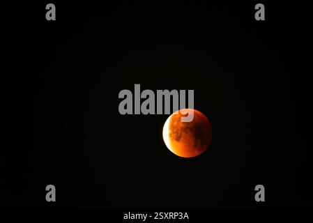 A glowing blood moon during a partial lunar eclipse at night. Stock Photo