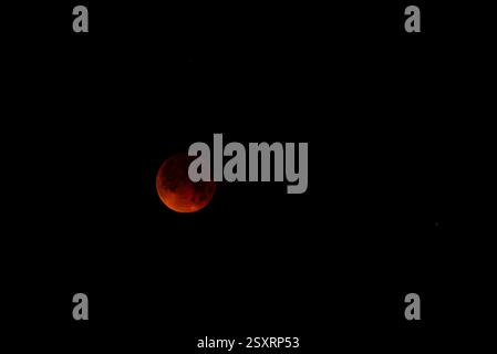 A glowing blood moon during a partial lunar eclipse at night. Stock Photo