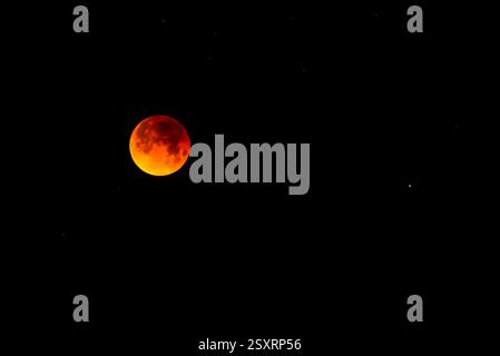 A glowing blood moon during a partial lunar eclipse at night. Stock Photo