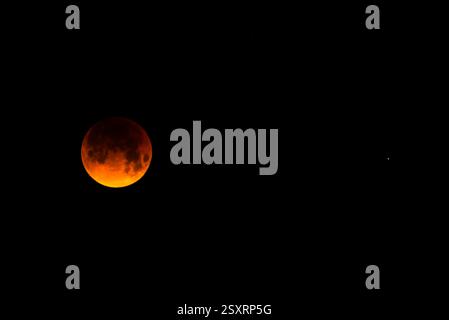 A glowing blood moon during a partial lunar eclipse at night. Stock Photo