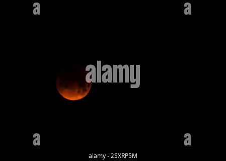 A glowing blood moon during a partial lunar eclipse at night. Stock Photo