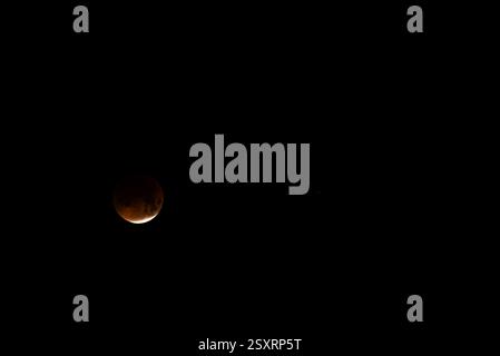 A glowing blood moon during a partial lunar eclipse at night. Stock Photo