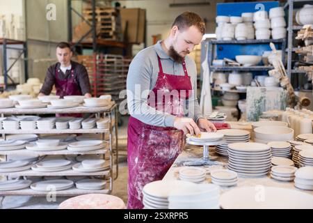 Ceramicist using sponge to clean pottery plates in artisanal workshop Stock Photo