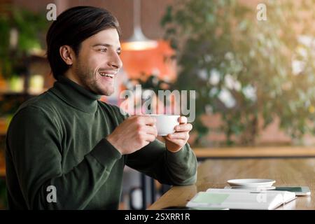 Dreamy freelancer looking for new opportunities, drinking coffee Stock Photo