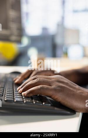 Startup employee sitting at desk in office, typing on keyboard, solving project with deadline approaching. Close up of person writing code at computer in workspace, solving tasks during job shift Stock Photo