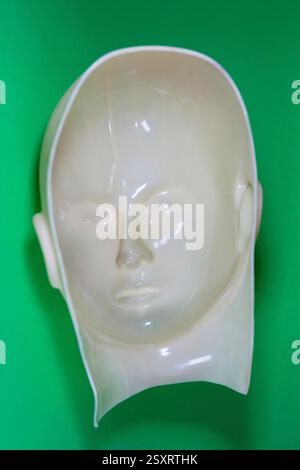 A surreal looking inside out rubber face mask on a green background. Stock Photo