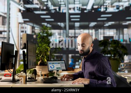 Middle eastern employee overseeing administrative tasks at desk, reviewing organizational performance metrics for success. Skilled manager analyzing data focused on strategic planning. Stock Photo
