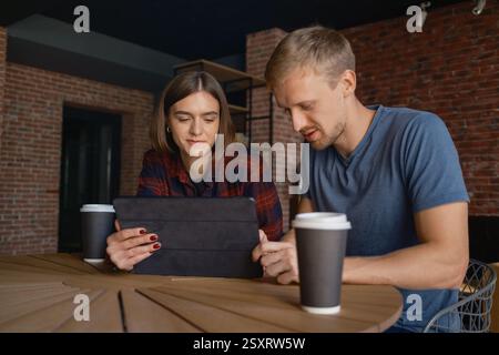 Two friends sharing a collaborative moment with a tablet in a coffee shop Stock Photo