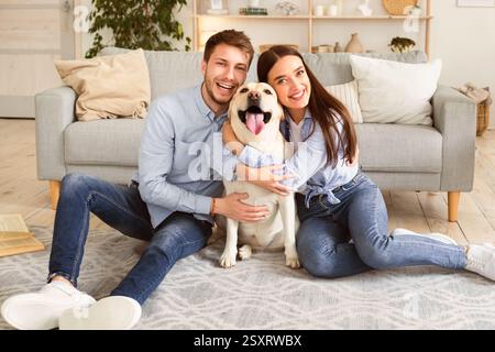 Young happy spouses with dog posing at home Stock Photo