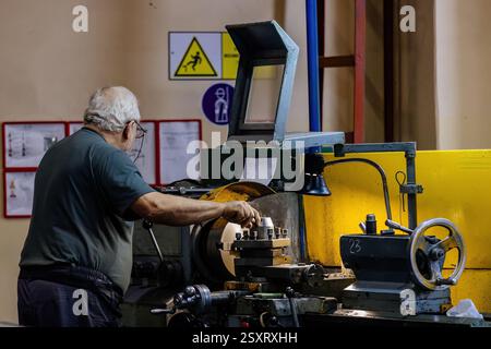 Factory worker working on lathe in metalworking factory. Stock Photo
