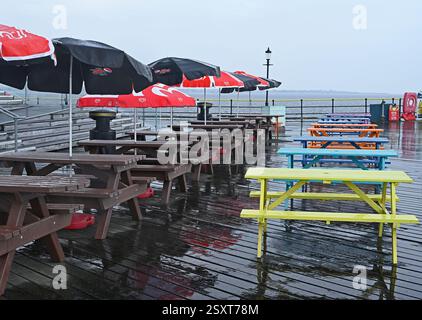 Parasols and coloured tables on a wet day at the Pier Head on the longest pleasure pier in the world, Southend on Sea, City of Southend. UK Stock Photo