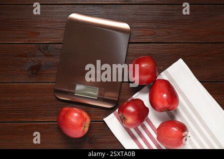 Electronic kitchen scale and apples on wooden table, flat lay Stock Photo