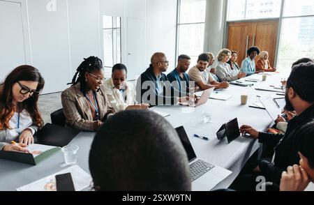 Diverse group of people engaged in a business meeting, discussing ideas and collaborating in a modern company office. Stock Photo