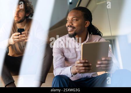 Smiling busy young African American business man, manager using tablet computer Stock Photo