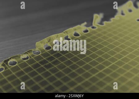 Yellow notebook page resting on desk with torn edge Stock Photo
