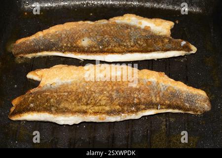 Close up of crispy fish skin frying in a pan being cooked Stock Photo