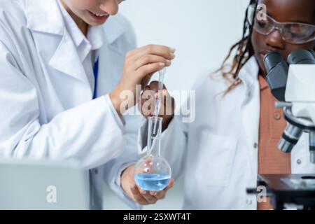 Diverse researchers in laboratory holding reagent tube and analyzing fluid samples Stock Photo