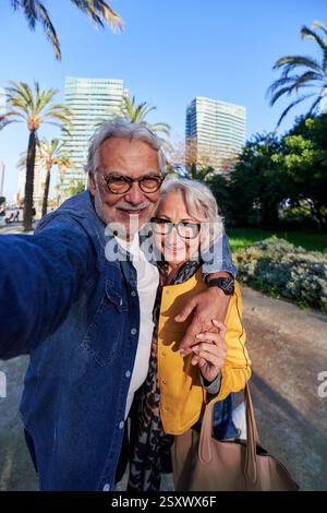 Senior couple taking a cheerful selfie in a park in the city center. Stock Photo