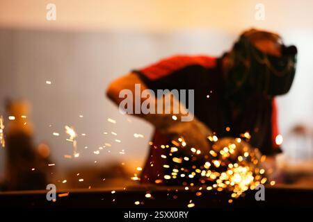 Industrial Worker Welding Metal With Spark Flying in a Manufacturing Workshop Stock Photo