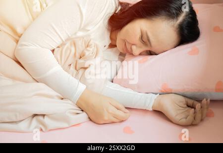 Attractive Asian woman sleep and sweet dream lying on bed in cozy bedroom in the morning. Sleep and Rest Healthcare Concept Stock Photo