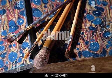 selection of artist's paint brushes on colourful book inside pages Stock Photo