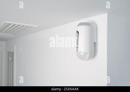 a motion detector equipped with a camera, mounted on a wall, indoors, as part of a burglar alarm system Stock Photo
