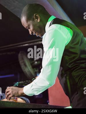 Pouring drinks with smile, bartender at lively nightclub bar serving patrons Stock Photo