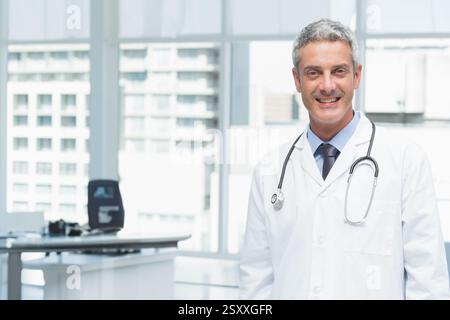 Smiling doctor in white coat standing confidently in modern office, copy space Stock Photo