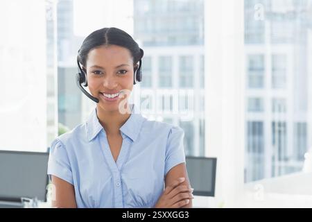 Wearing headset, businesswoman working in modern office, smiling while talking Stock Photo