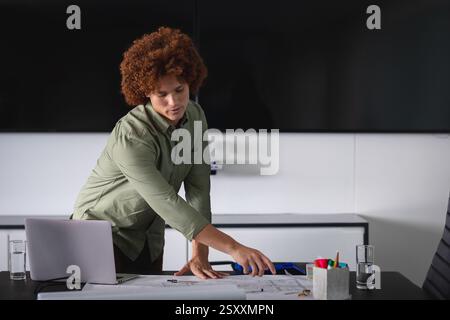 Business professional analyzing documents on desk with laptop in modern office Stock Photo