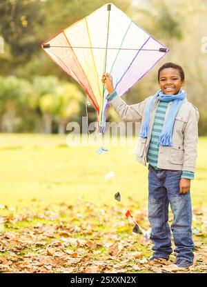 Smiling African American boy holding colorful kite in autumn park, copy space Stock Photo