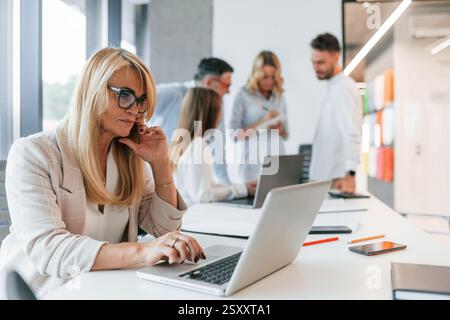 Woman working by using laptop. Group of professional business people is in the office. Stock Photo