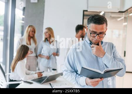 Portrait of senior man. Group of professional business people is in the office. Stock Photo