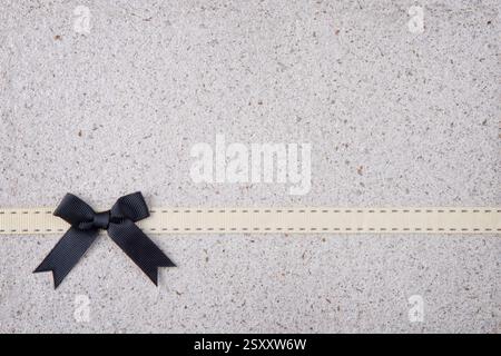 Retro Black Ribbon and Bow Over Real Hand Made Paper Background Stock Photo