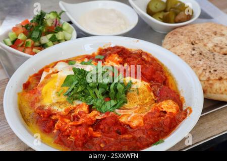 Israeli cuisine. Shakshuka lunch - poached eggs in spicy pan fried tomatoes. Stock Photo