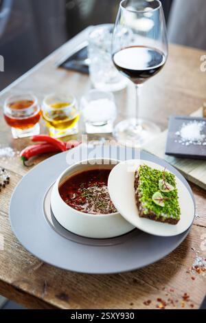Borscht soup. Black Angus beef, beetroot, sour cream, toasted bread with smalec in a bowl. Delicious healthy food closeup served for lunch on a table Stock Photo