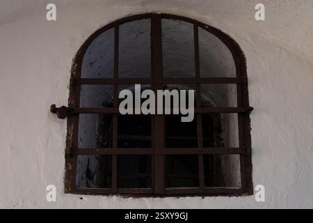Arched window with bars on yellow antique wall Stock Photo